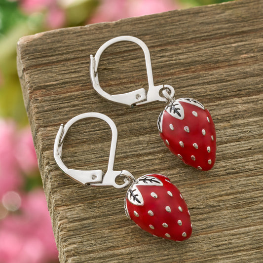 Hand-painted red enamel strawberry leverback earrings on rustic wood background